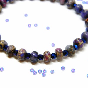 Pu&ograve; includere: Un braccialetto con perline a motivi viola e marrone con accenti blu scuro. Il braccialetto &egrave; composto da perline rotonde ed &egrave; infilato su un cordoncino elastico trasparente.
