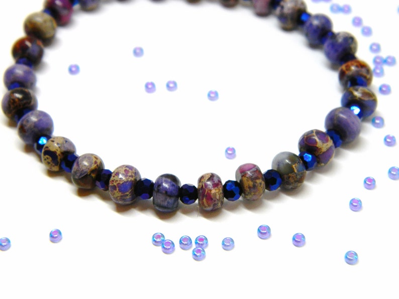 Pu&ograve; includere: Un braccialetto con perline a motivi viola e marrone con accenti blu scuro. Il braccialetto &egrave; composto da perline rotonde ed &egrave; infilato su un cordoncino elastico trasparente.