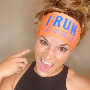 May include: A woman wearing a black tank top and an orange headband with the text "I RUN TO GET THE CRAZY OUT" in blue lettering.