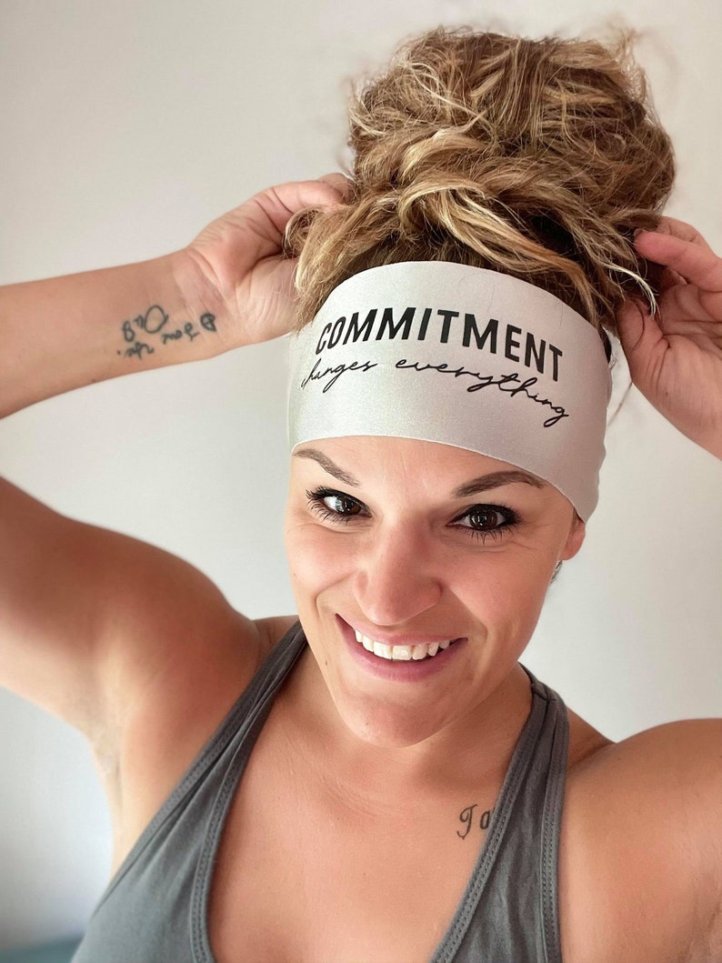 Op de afbeelding: Een zilveren hoofdband met de tekst "COMMITMENT changes everything" in zwarte letters.