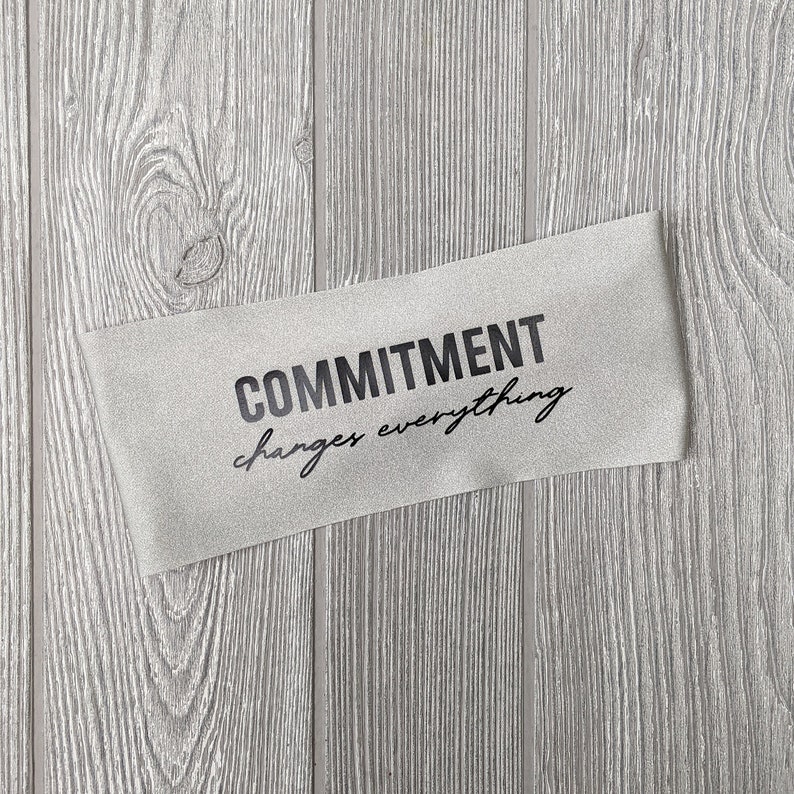Op de afbeelding: Een grijze stoffen banner met de tekst "COMMITMENT changes everything" in het zwart gedrukt.
