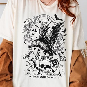 Könnte beinhalten: Ein weißes T-Shirt mit einem schwarzen Grafikdesign, das einen Raben, Schädel und den Text "My Anomaly You Are Valtem For Atys" zeigt.
