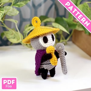 May include: Crocheted figure of a character with a yellow hat, gray body, white face, and purple cape. The figure is holding a yellow object and a gray staff. The text "PATTERN" is visible in the upper right corner, and "PDF File" in the lower left.