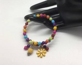 Divertida pulsera en espiral de alambre con memoria y cuentas multicolores brillantes con pompón amarillo y dije floral