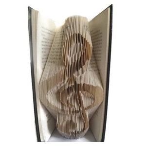 May include: A book with the pages folded into the shape of a treble clef. The book is open and the pages are folded to create a three-dimensional shape.