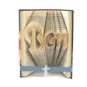 May include: A book with the name "Ben" folded into the pages. The book is open and standing upright. The pages are folded to create the letters of the name.