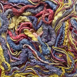 May include: Close-up of a textured textile with a variety of colorful yarns. The yarns are in shades of blue, yellow, pink, and purple, creating a dense, tactile surface. The image showcases the intricate details of the yarn.