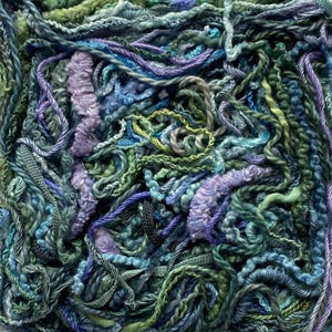Könnte beinhalten: Nahaufnahme eines textilen Kunstwerks. Das Kunstwerk zeigt eine dichte Anordnung verschiedener Garne in Grün-, Blau- und Lilatönen. Die Garne sind verdreht, geflochten und geschlungen, wodurch eine taktile und visuell reiche Oberfläche entsteht.