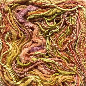 May include: Close-up of a textured fiber art piece. The artwork features a mix of yarns in various shades of yellow, orange, pink, and green. The yarns are arranged in a dense, interwoven pattern, creating a tactile and visually rich surface.