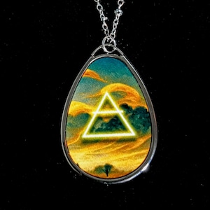 May include: Silver-toned necklace with a teardrop pendant. The pendant features a colorful landscape with a glowing white triangle. The chain is a delicate beaded style, and the background is black.