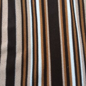 May include: A striped fabric with alternating brown, beige, and light blue stripes. The fabric has a soft, fuzzy texture.