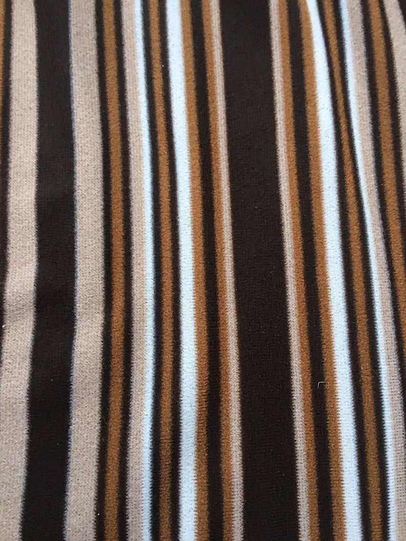 May include: A striped fabric with alternating brown, beige, and light blue stripes. The fabric has a soft, fuzzy texture.