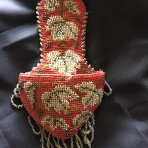 May include: A vintage beaded purse with a floral design. The purse is made of red fabric and has a beaded fringe.