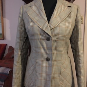 May include: A brown and white plaid blazer with two pockets and three buttons. The blazer is on a mannequin.
