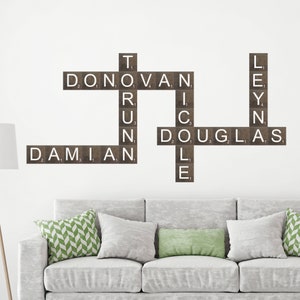May include: A wall decor featuring a scrabble tile word art with the names Damian, Donovan, Douglas, and Leyn. The tiles are brown with white letters.