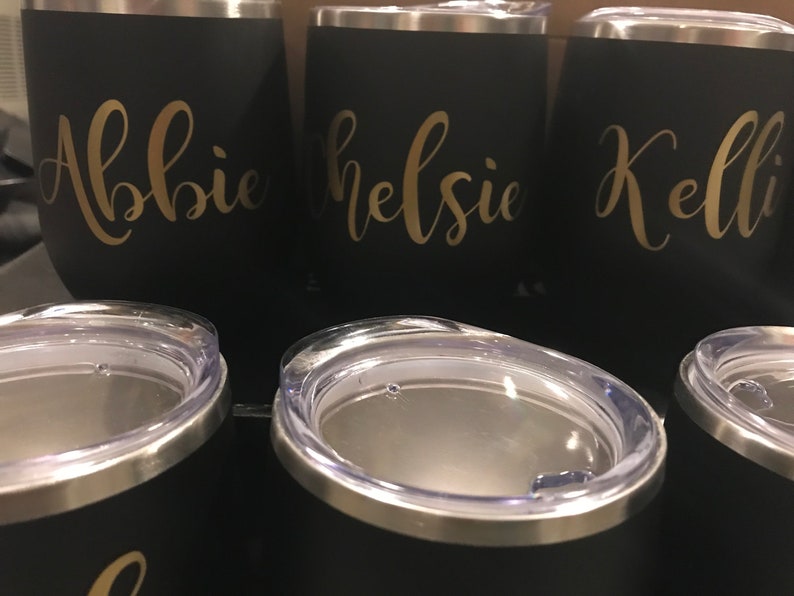 May include: Three black stainless steel tumblers with gold lettering. The tumblers are labeled "Abbie", "Kelsie", and "Kelli".
