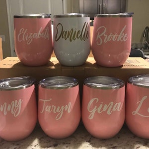 May include: Eight stainless steel wine tumblers with personalized names: Elizabeth, Danielle, Brooke, Jenny, Taryn, Gina, Lexi. The tumblers are pink with white lettering.