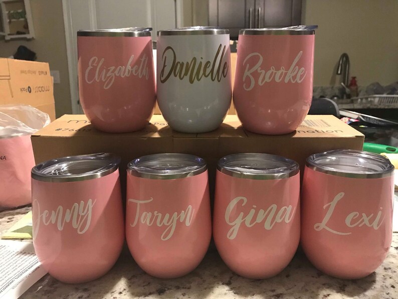 May include: Eight stainless steel wine tumblers with personalized names: Elizabeth, Danielle, Brooke, Jenny, Taryn, Gina, Lexi. The tumblers are pink with white lettering.