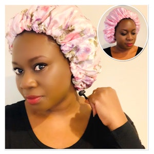 May include: A pink satin sleep cap with a floral print. The cap has a drawstring to adjust the fit.