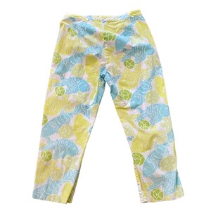 Puede incluir: Pantalones blancos con estampado de peces azules y amarillos.