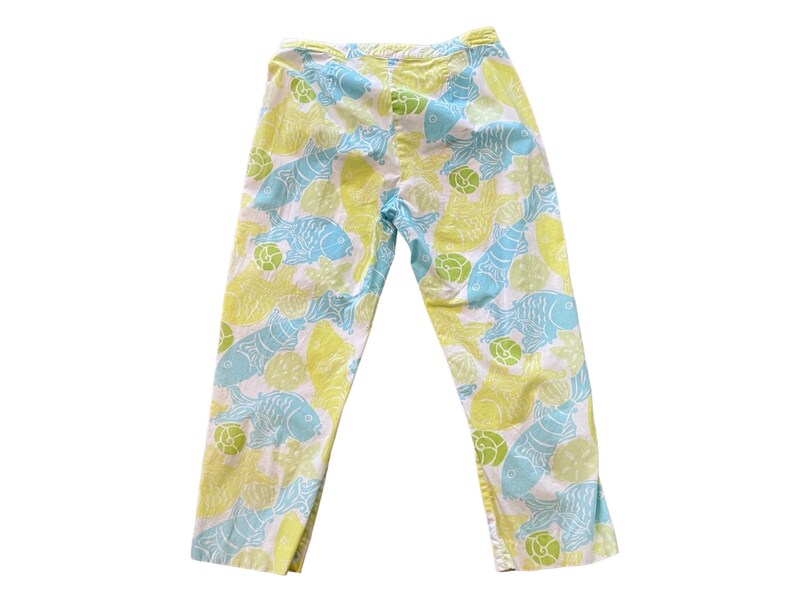Puede incluir: Pantalones blancos con estampado de peces azules y amarillos.