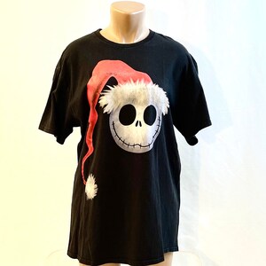 May include: Black t-shirt with a graphic of Jack Skellington from The Nightmare Before Christmas wearing a Santa hat.