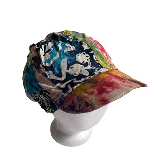 May include: A colorful patchwork baseball cap with a tie-dye brim. The cap is made of different fabrics and has a variety of patterns, including floral and geometric designs.