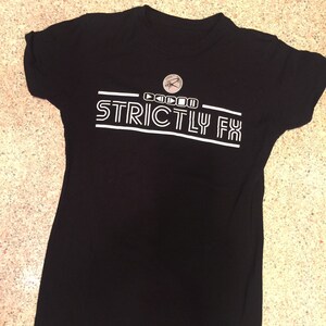 May include: Black t-shirt with white text that reads "Strictly FX" with a small logo above the text.