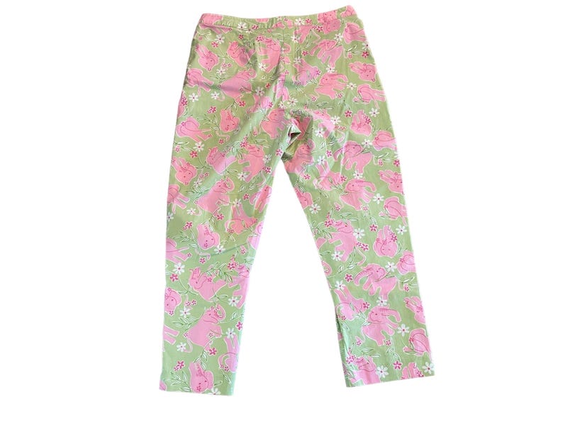 May include: Green pants with a pink bunny rabbit print. The pants have a relaxed fit and a cropped length.