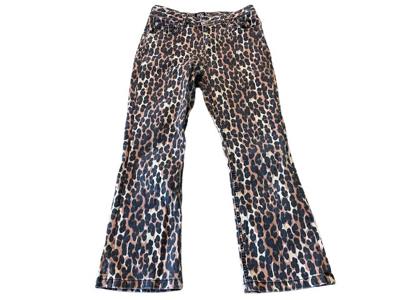 Op de afbeelding: Een paar bruine en zwarte jeans met luipaardprint en een wijde pijp.