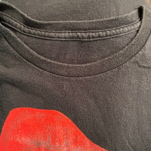 May include: Black t-shirt with a red and white graphic of Santa Claus's face.