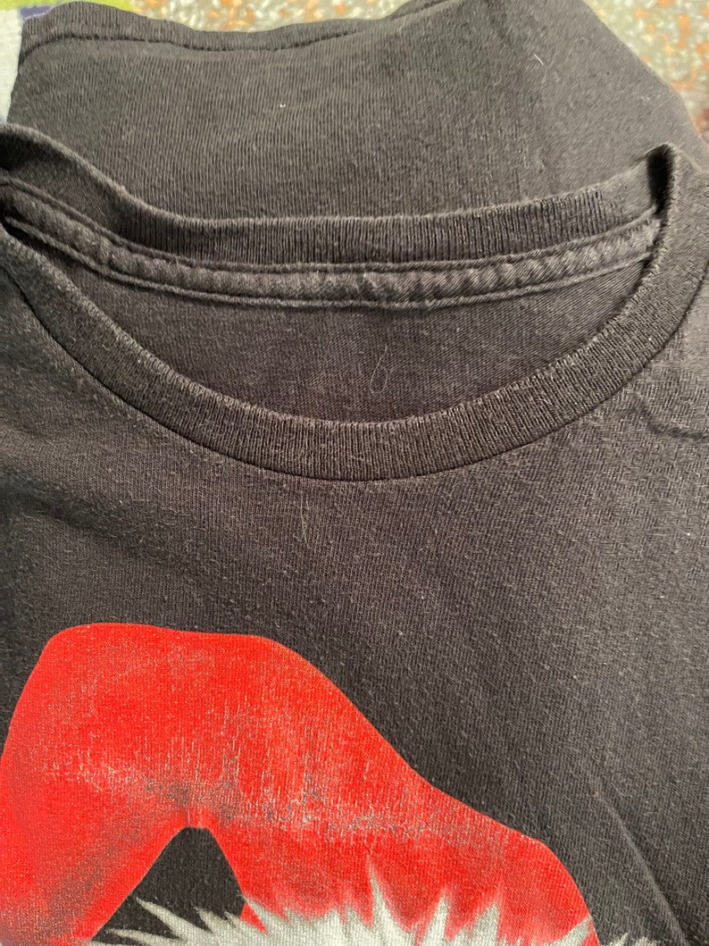 May include: Black t-shirt with a red and white graphic of Santa Claus's face.