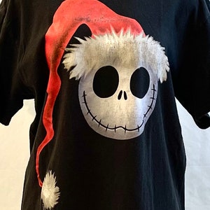 May include: Black t-shirt with a white and red graphic of Jack Skellington from The Nightmare Before Christmas wearing a Santa hat.