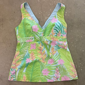 May include: A sleeveless, light blue and green top with a tropical print featuring pink flowers and green leaves.