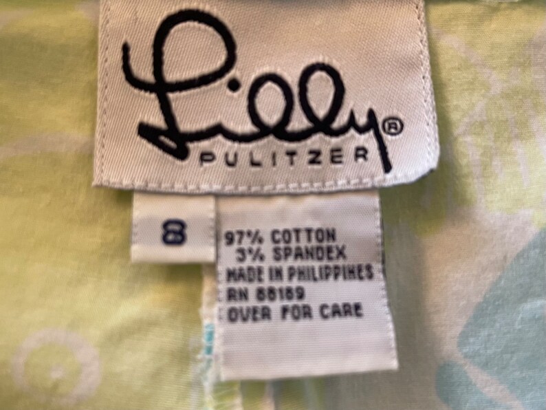Puede incluir: Una etiqueta blanca con texto negro que dice "Lilly Pulitzer" y una etiqueta de talla 8. Una etiqueta blanca con texto negro indica que la composici&oacute;n de la tela es 97% algod&oacute;n y 3% spandex. La etiqueta tambi&eacute;n indica "Hecho en Filipinas" y "RN 88189". La etiqueta indica "Dar la vuelta para el cuidado".