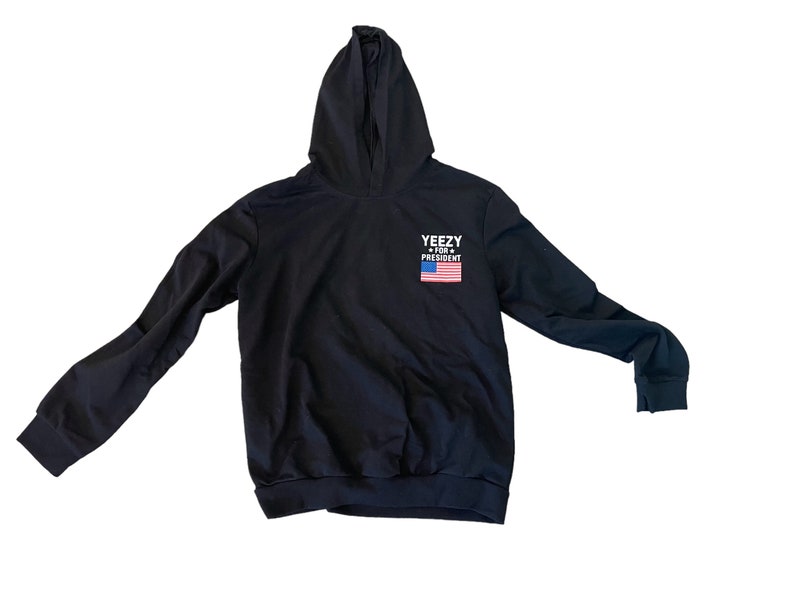 May include: Black hooded sweatshirt with the text "YEEZY FOR PRESIDENT" and an American flag graphic.