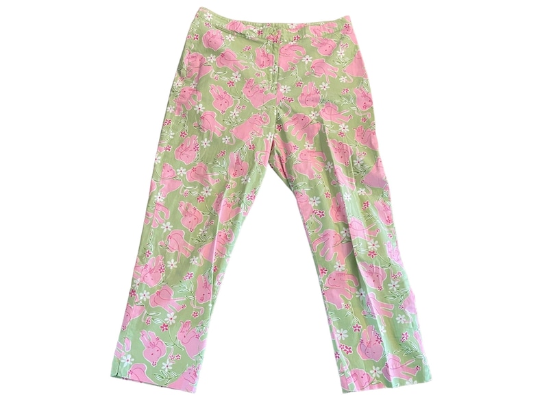 May include: Green pants with a pink and white floral pattern featuring cartoon pigs.