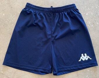 May include: Navy blue athletic shorts with a white Kappa logo on the right leg.