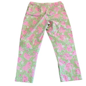 May include: Green pants with a pink and white pattern of elephants. The pants have a relaxed fit and a cropped length.