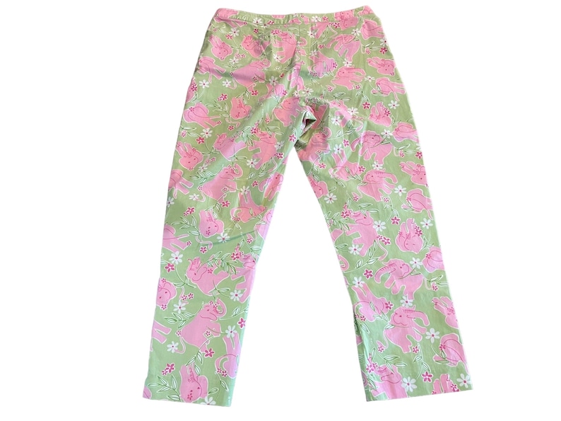 May include: Green pants with a pink and white pattern of elephants. The pants have a relaxed fit and a cropped length.