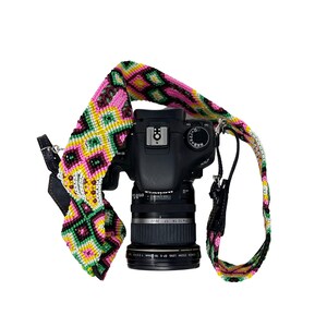 May include: A black Canon camera with a colorful, woven camera strap. The strap is pink, green, and yellow with a geometric pattern.