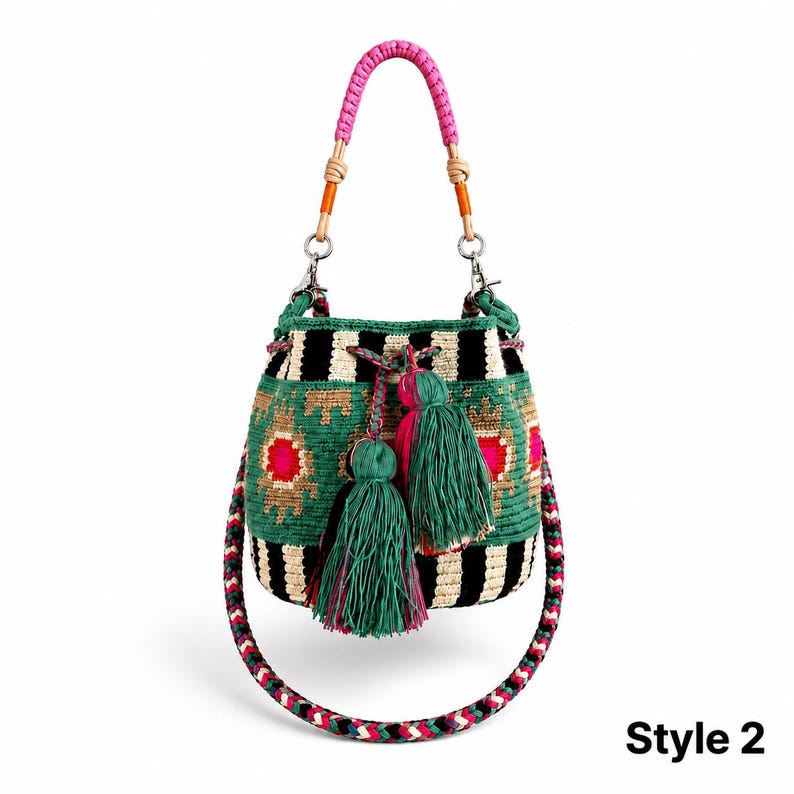 May include: A bucket bag featuring a woven pattern of black and cream stripes with green, pink, and tan geometric accents. The bag includes a pink braided handle, a long multi-colored shoulder strap, and two large green tassels. Text reads Style 2.