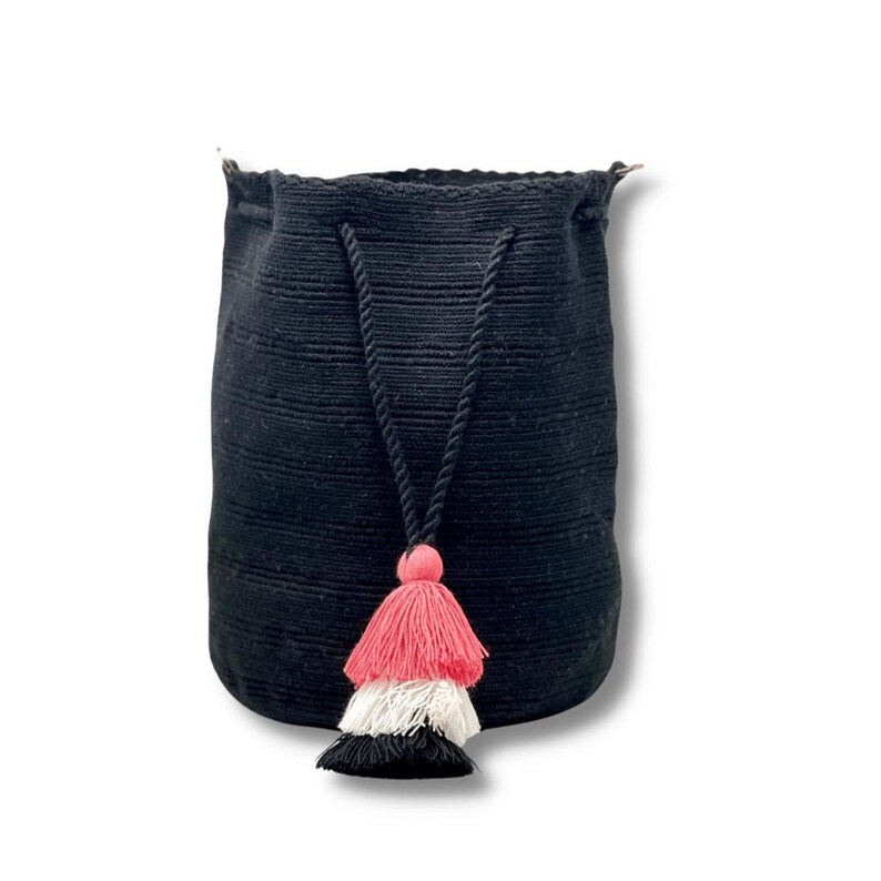 May include: Black drawstring bag with a pink, white, and black tassel. The bag is made of a woven material and has a long strap.