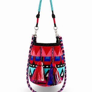 May include: A bucket bag featuring a vibrant woven pattern in red, black, blue, and turquoise. The bag includes a braided turquoise handle, a multi-colored braided shoulder strap, and two large tassels in red, blue, and white. Text reads Style 1.