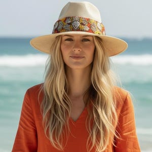 Model wearing handmade straw fedora hat with Oaxacan knitted band and silver heart charms for boho summer style