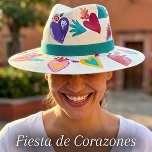 Model wearing colorful hand painted Mexican fedora hat with heart designs in lifestyle setting