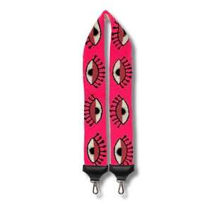 May include: A pink adjustable camera strap with a repeating pattern of black outlined eyes with red and white details.