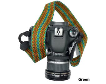 May include: A black DSLR camera with a patterned strap in green, orange, and blue. The strap has a zig-zag design. The word "Green" is printed in the bottom right corner of the image.