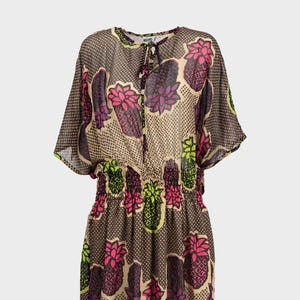 Peut inclure: Une robe en mousseline brune avec un imprimé ananas. La robe a un nœud au cou et une taille élastique.
