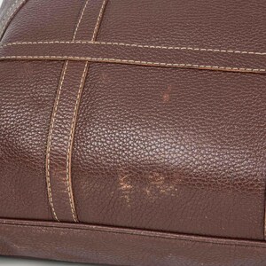 May include: A brown leather tote bag with a stitched design. The bag has a textured surface and appears to be well-worn.